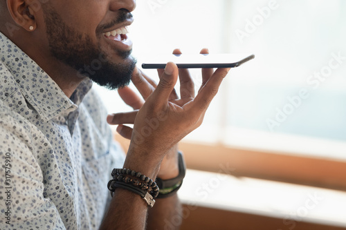 Картината върху платно Closeup view african guy talking with friend on speakerphone