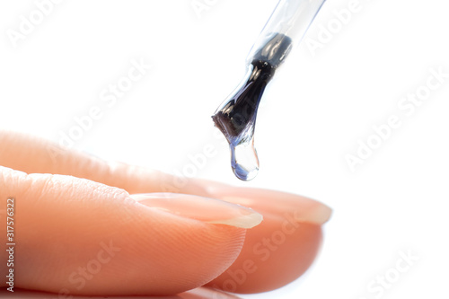 Macro photo manicure drop of varnish  master applies gel with brush on nails of girl white background