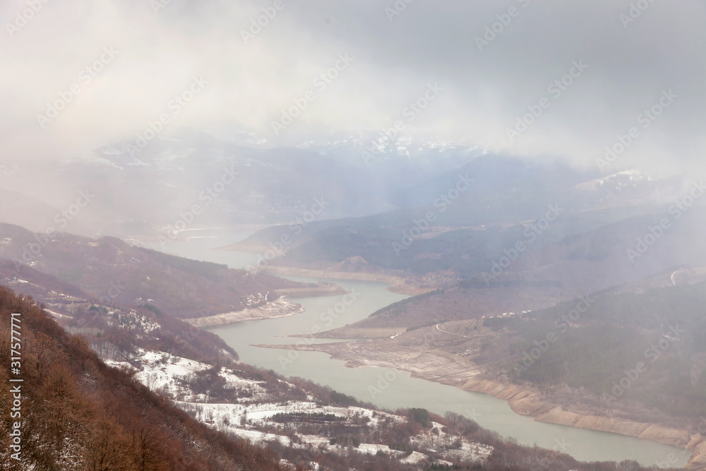 Soft, stunning view from Goat rock (Kozji kamen) viewpoint of meandering Zavoj lake (Zavojsko jezero) during a misty, moody winter morning