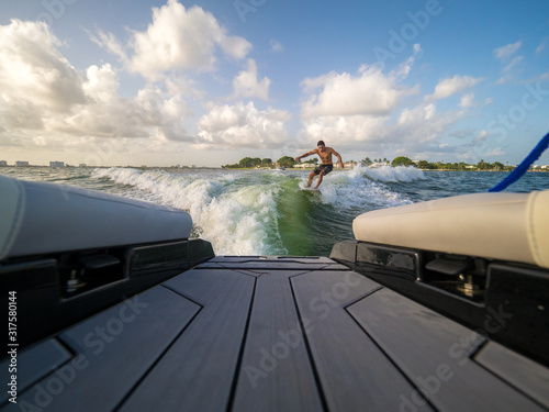 male wake surfing wave behind boat at sea photo