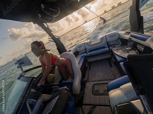 Couple having fun wakesurfing at sunset in Miami, fast boat and man being pulled by rope photo