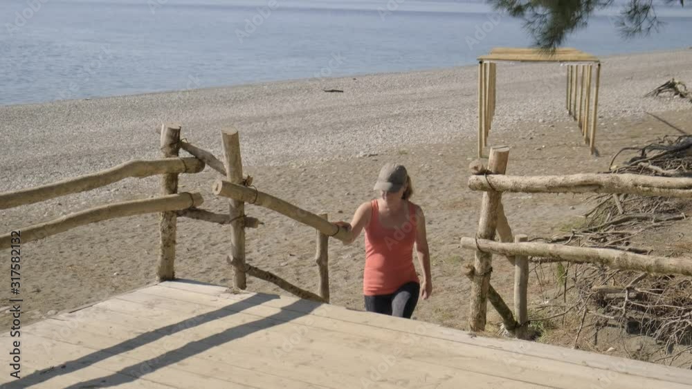 adult woman climbs stairs to wooden platform on seashore. adult woman climbs stairs to wooden platform on seashore.