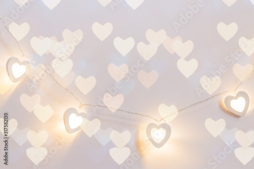 Wooden eart-shaped harland on pink background with bokeh lights. Greeting card for st valentine's day, Copy space photo