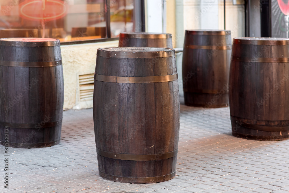 brown wooden wine barrel on the street on stone paving slabs, bar restaurant decorations close up nobody. brown wooden wine barrel on the street on stone paving slabs, bar restaurant decorations close up nobody.