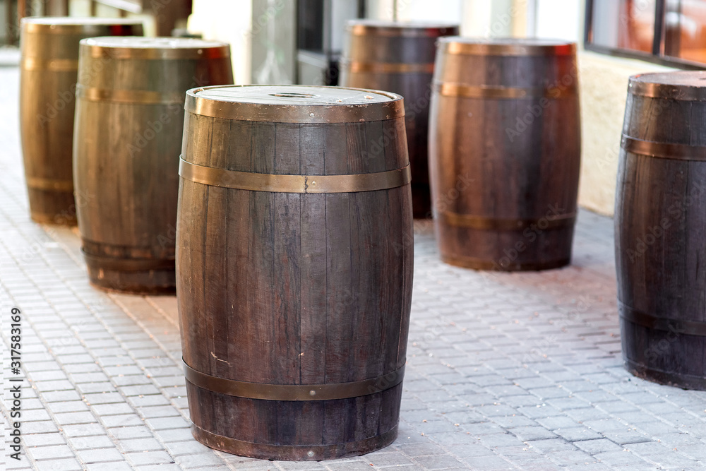 brown wooden barrel on the city street on stone tile, row of cask decorations close up nobody. brown wooden barrel on the city street on stone tile, row of cask decorations close up nobody.