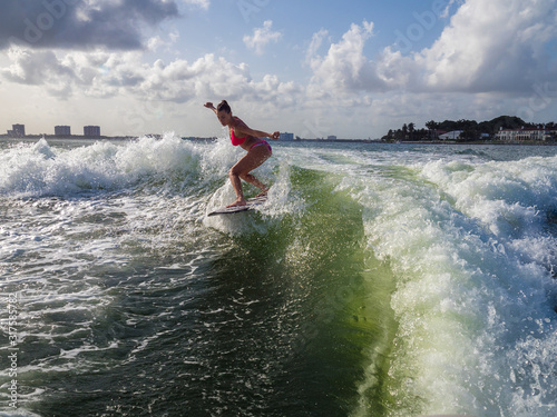 Sticker Pretty woman balances over wave, wakesurfing at sea, water splashing