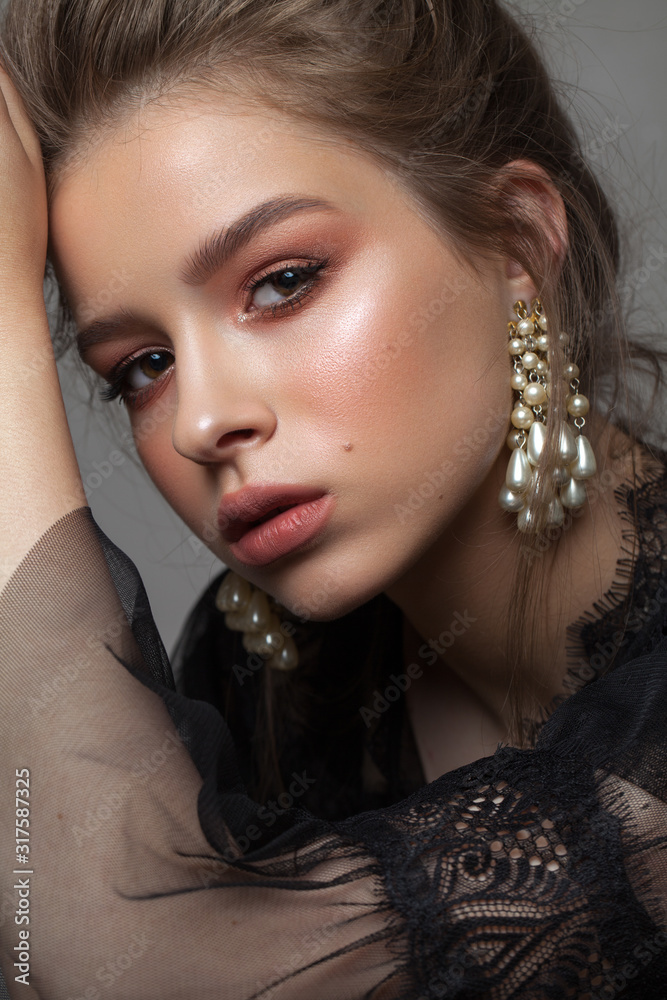 Obraz premium Portrait of a beautiful girl in black lace dress with evening professional coral red make up and pearl earrings.