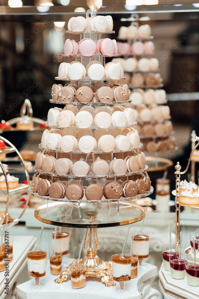 Delicious wedding reception candy bar dessert table. Candy bar for the wedding. Wedding decoration with pastel colored cupcakes, meringues, muffins and macarons.