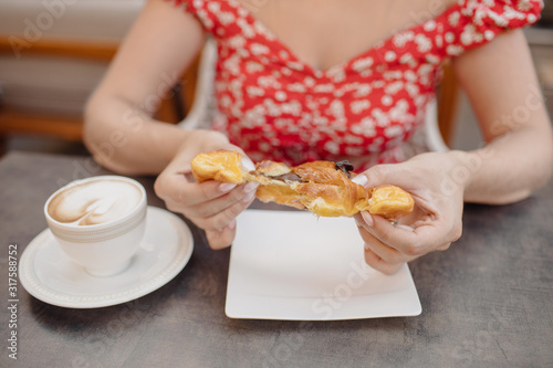 Woman eating and dividing fresh croissant.