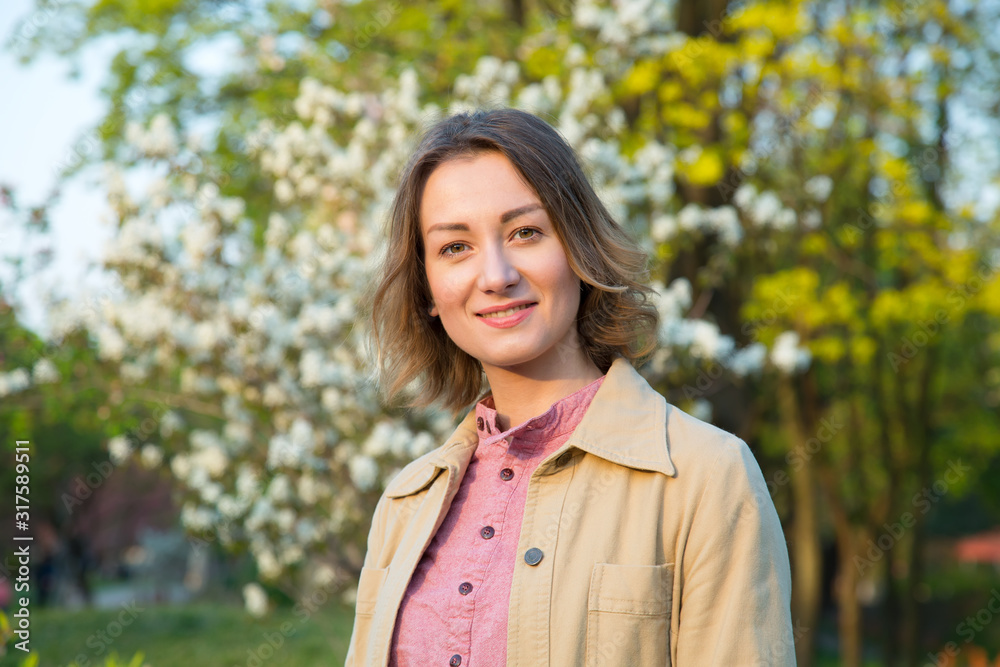 Portrait of a beautiful happy woman on the background of a spring blooming tree garden Portrait of a beautiful happy woman on the background of a spring blooming tree garden