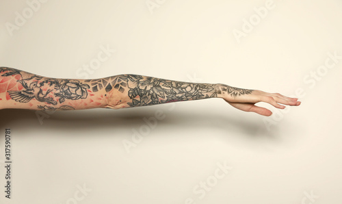 Woman with colorful tattoos on arm against white background, closeup