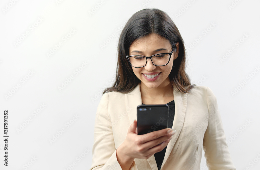Portrait of lovely joyful mixed race lady looking at smartphone screen holding it in one hand, isolated white background, front view Portrait of lovely joyful mixed race lady looking at smartphone screen holding it in one hand, isolated white background, front view