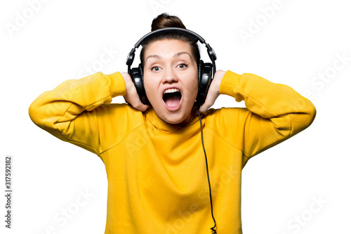 Girl holds hands on big headphones in which music plays. isolated