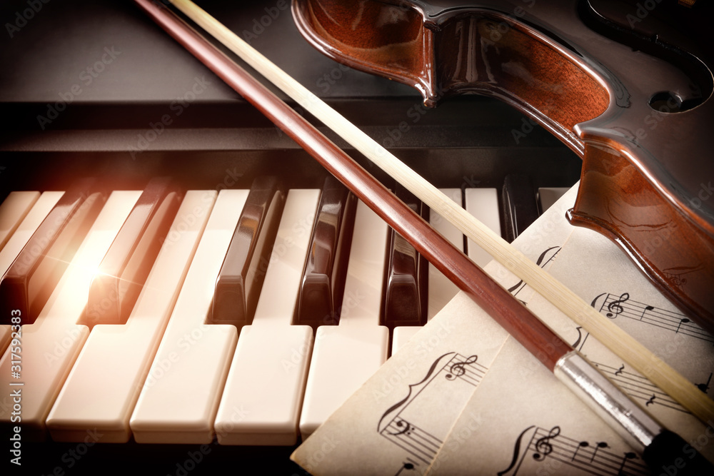 Fototapeta premium Violin bow and sheet music on piano keys front view