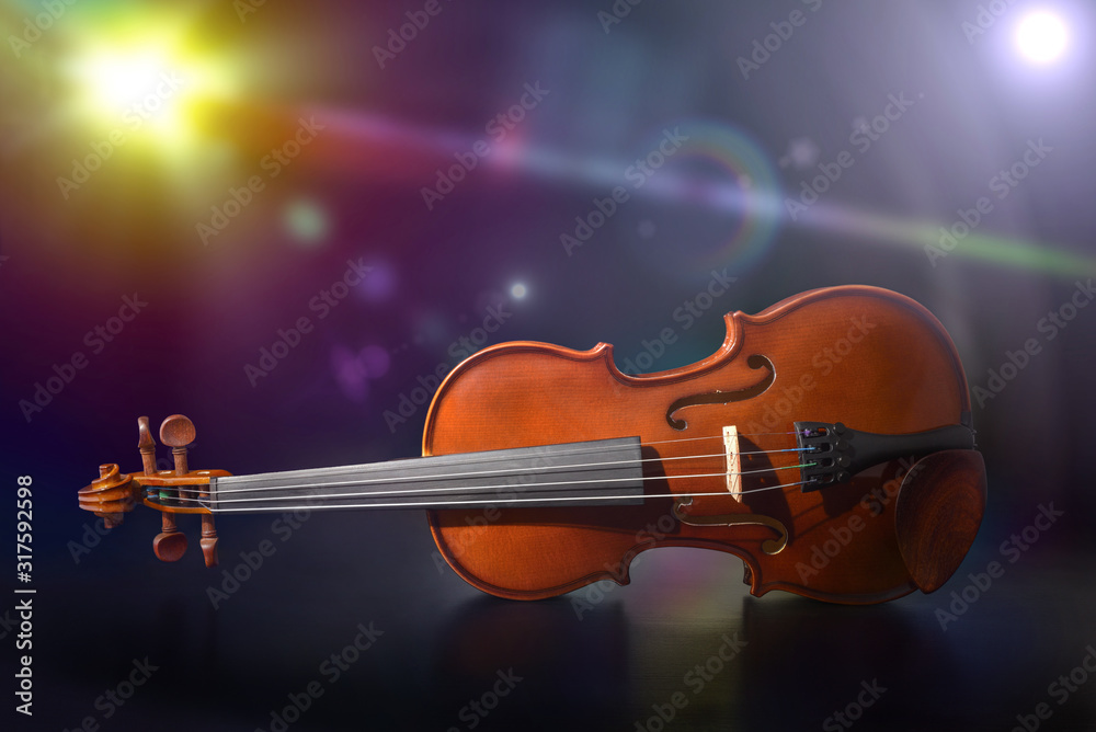 Violin on black wooden table on stage with colorful lights