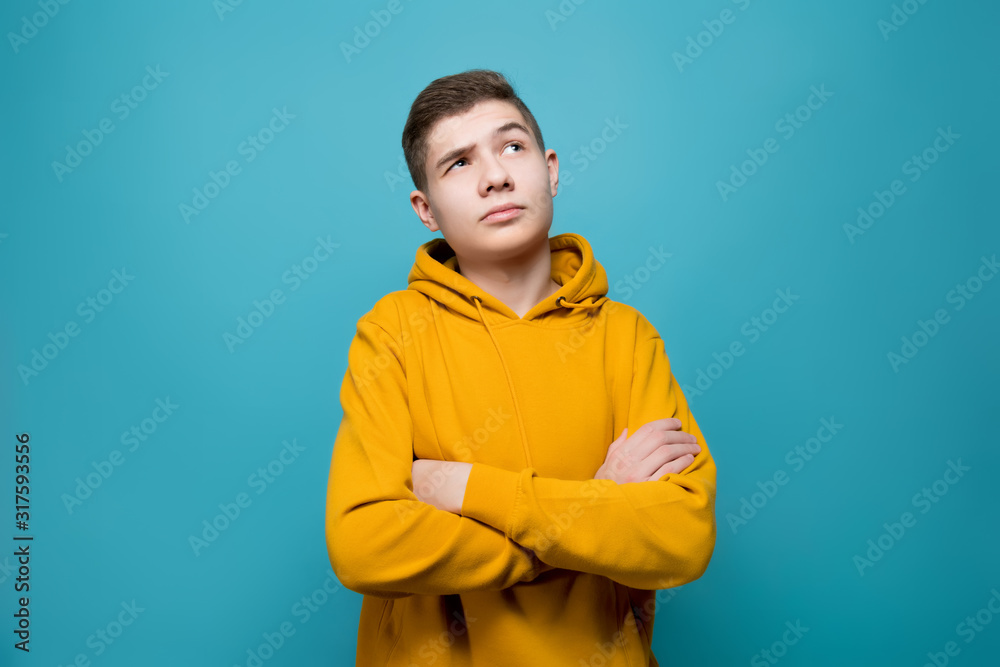 the guy in a sweatshirt folded his arms over his chest and looks up thoughtfully the guy in a sweatshirt folded his arms over his chest and looks up thoughtfully