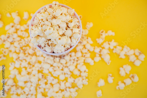 Butter popcorn in a red popcorn cup, snack in the house or cinema on a yellow background