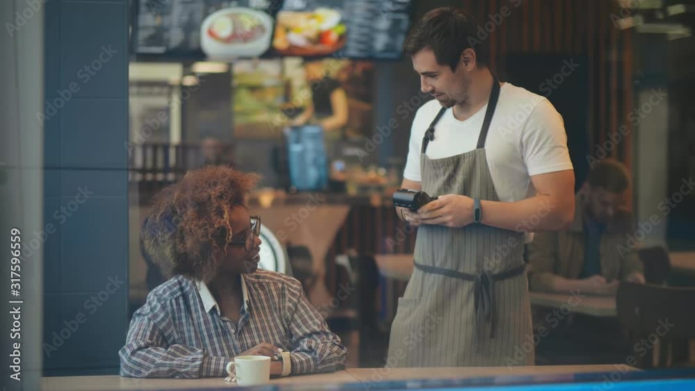 Woman using terminal for contactless payment with smartwatch in cafe