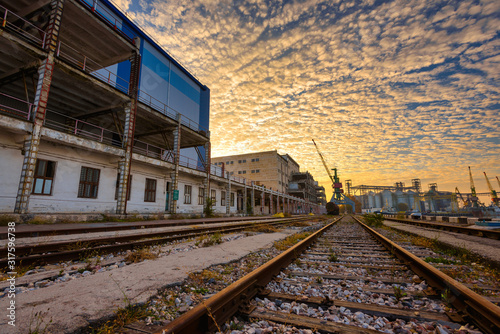 The territory of an old factory with railroad tracks at sunset