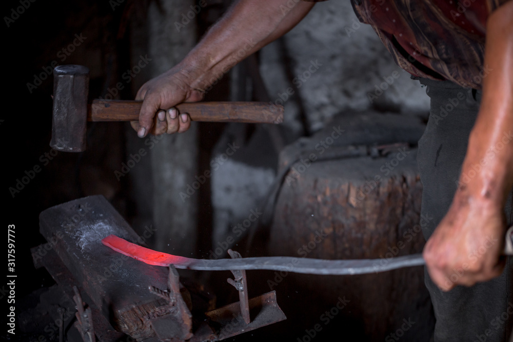 Blacksmith's hands at work. In one hand a hammer, in the other a