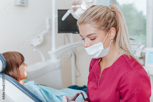 Female dentist in dental office treats teeth with kid patient