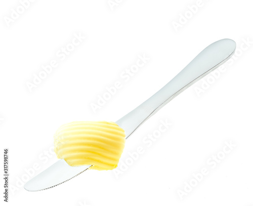 Butter on a knife for bread filling isolated on white background. Knife with fresh butter curl. Top view.