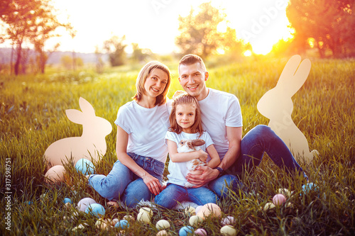 Little girl and her parents play with the rabbit. happy little girl holding cute fluffy Bunny. Friendship with Easter Bunny. Spring photo with beautiful young girl and her family with their Bunny.