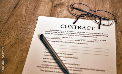 Contract sheet with glasses and pen on a wooden background
