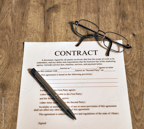 On the wooden table is the contract template. Sunglasses