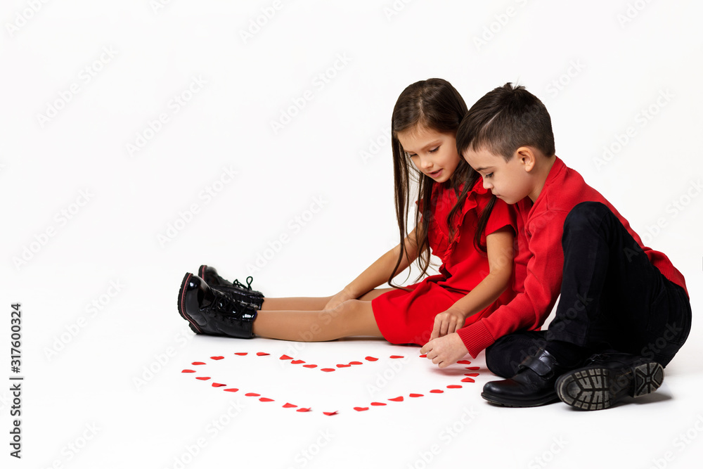 Φωτογραφία Happy romantic little couple girl and boy make a big heart shape out of small paper hearts on the floor isolated on white background