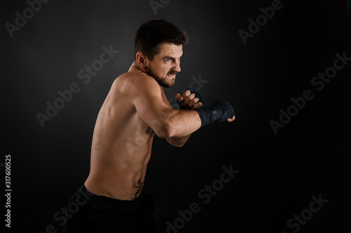 Sportsman boxer throwing a fierce and powerful punch. muscular man on black background.