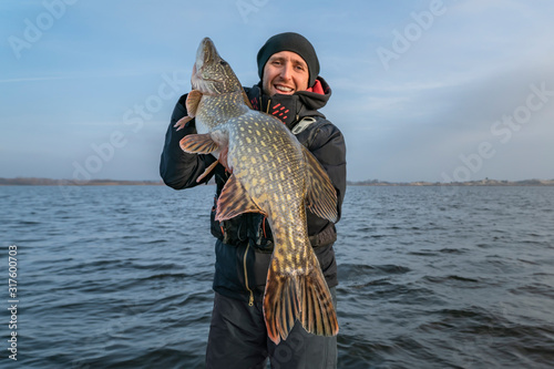 Pike fishing. Happy fisherman holding big fish at boat photo