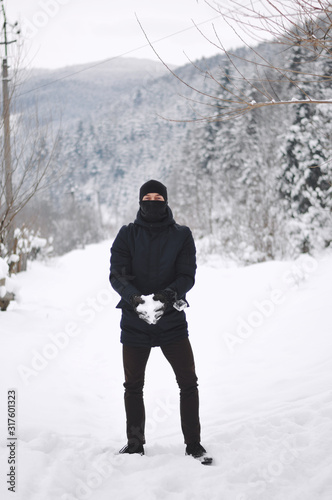 Hiker throwing snow high in the air at a mountain.