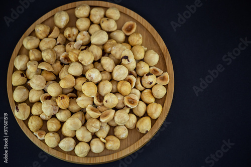 Hazelnut nut or noisettes nuts group Protein and healthy food for diet in a wooden plate on a black background.