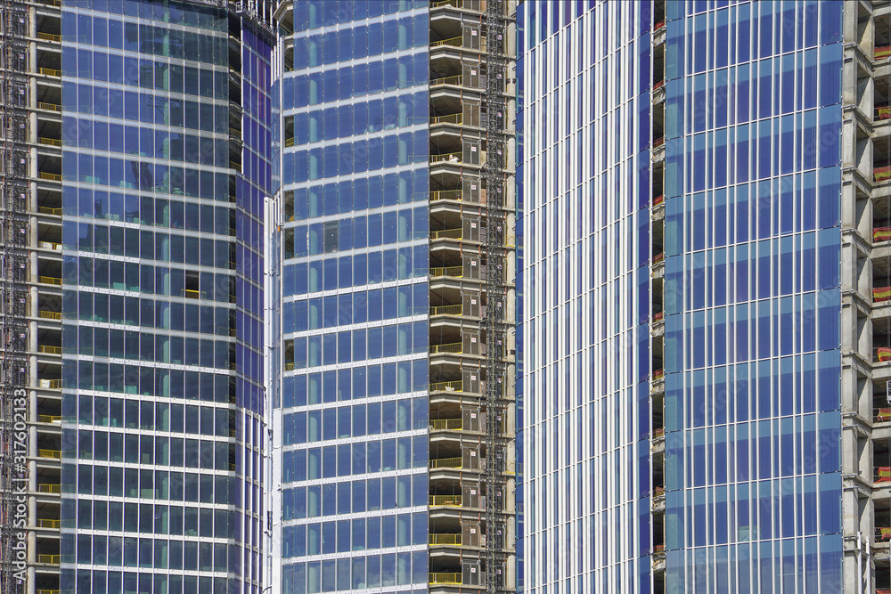 Modern new multi-storey building under construction in the city. Facade of a new multi storey building under construction with Windows and balconies and insulated walls.