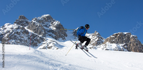 Skier jumping in front of rock mountains Meribel sun snowy mountain landscape France alpes 3 vallees