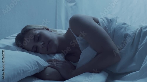 Young woman lying in the bed. Beautiful blond sleeping girl. Morning in the bedroom. Health and rest concept.