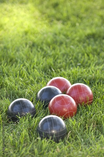 Vertical picture of colourful bocce balls on the lawn under the sunlight with a blurred background photo