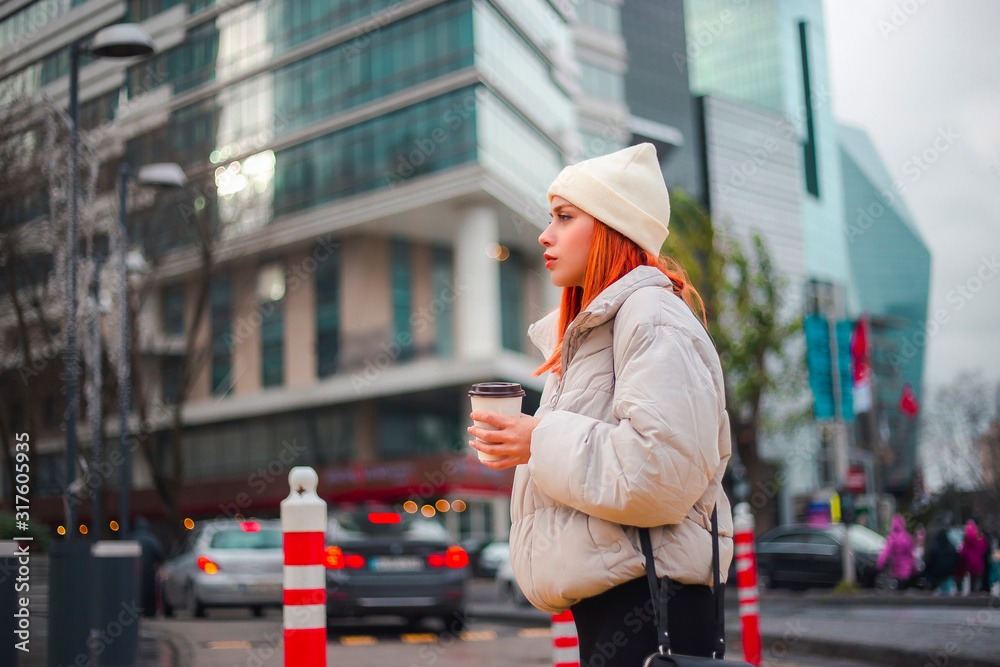 Attractive young stylish trendy redhead woman walking and crossing the road in a modern city