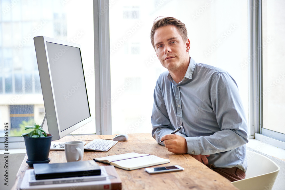 Young professional man at his desk looking at the camera