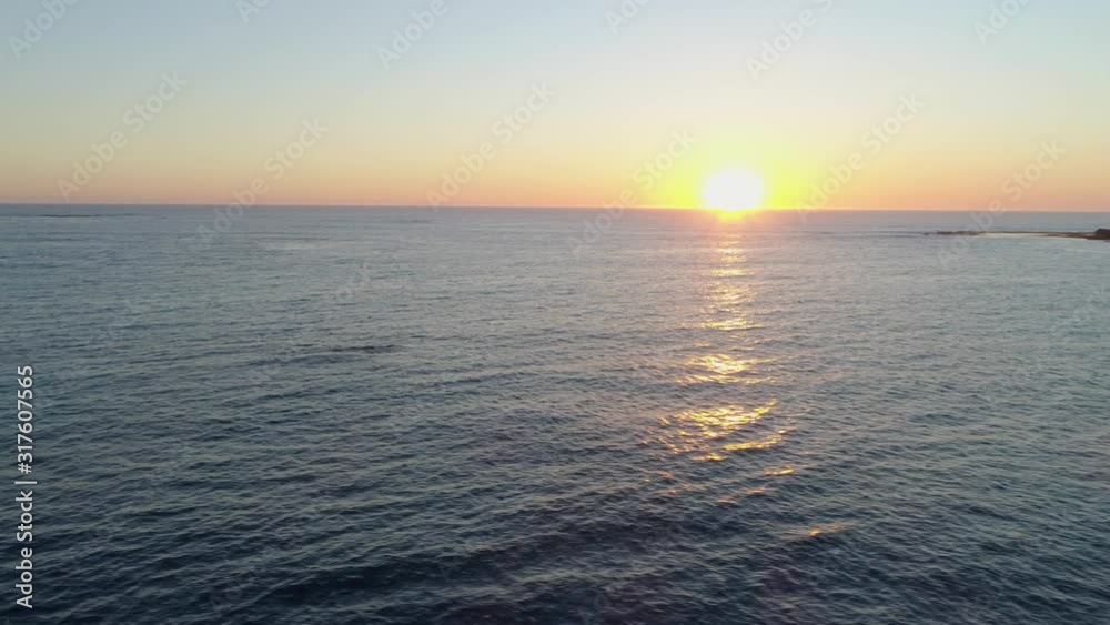 Aerial flight over sea facing the sun at sunset Aerial flight over sea facing the sun at sunset
