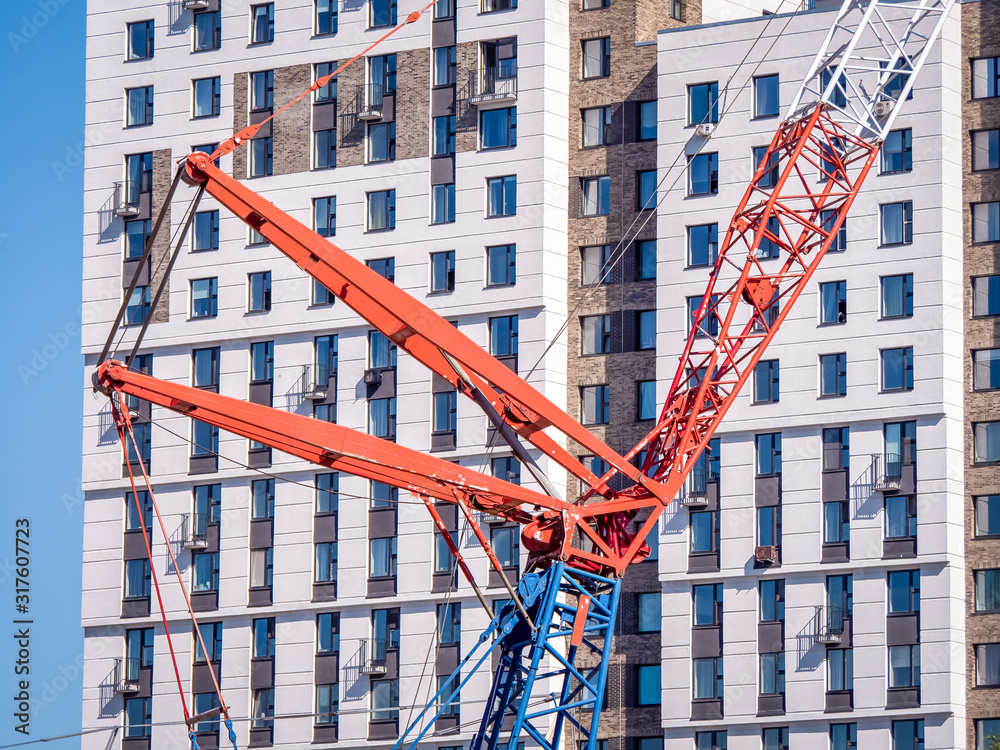 Construction crane on the background of a new modern residential building. Construction stages Construction crane on the background of a new modern residential building. Construction stages