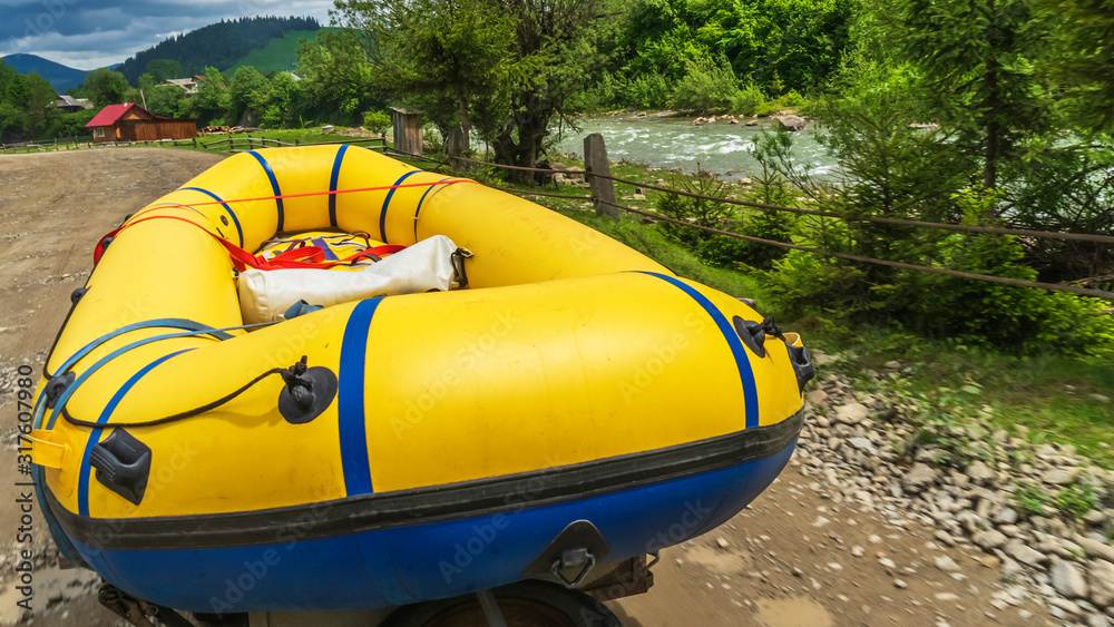 Big yellow rubber boat on the mountain road by riverside. Close-up photo. Rafting on mountain rivers. Extreme and activity concept.