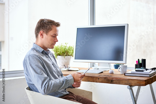 Businessman looking at his phone while sitting at his desk