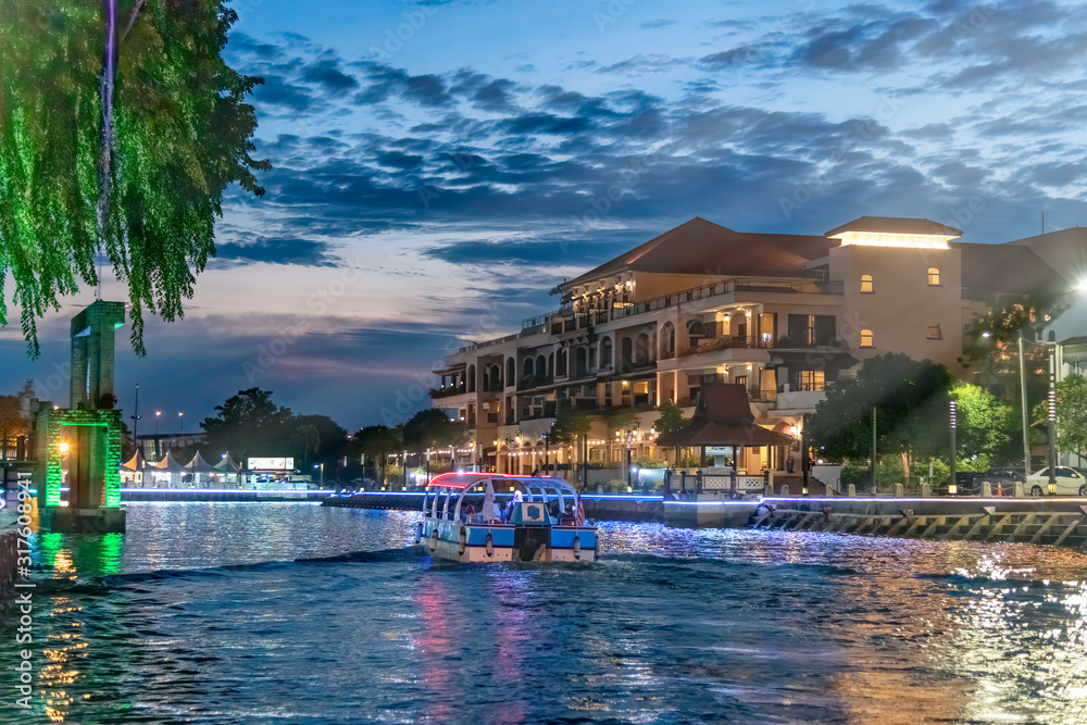 Sunset view of Melaka riverfront from a cruise boat. Malacca River and city skyline at night, Malaysia
