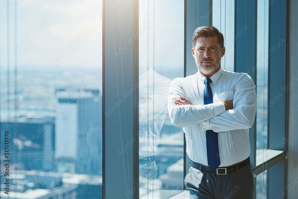 Fototapeta premium Mature businessman with arms crossed looking serious and confident