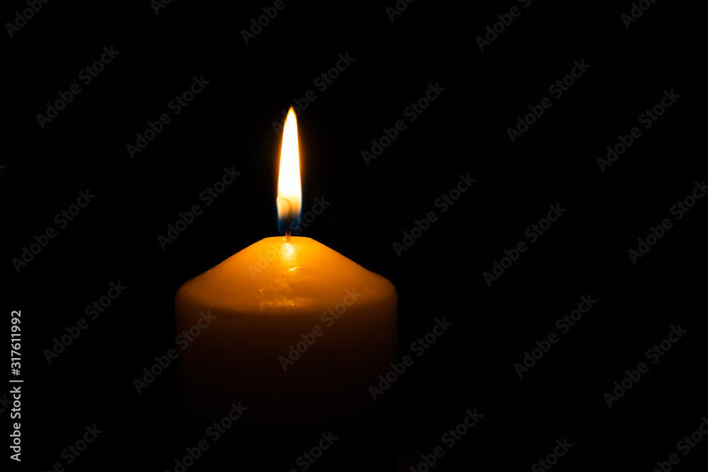 Single burning wax candle flame isolated on the black background