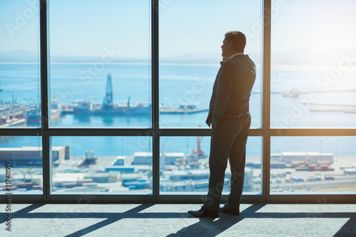 Confident businessman looking at view of harbour while on phone