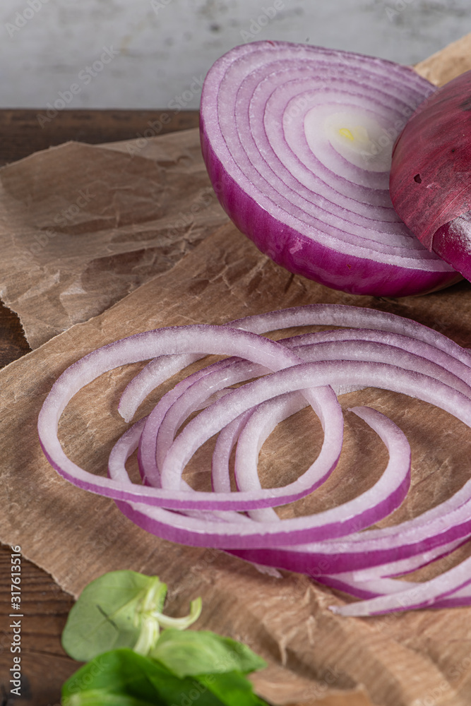 Wooden cutting board on old wooden table top with tablecloth, sliced red onion and cucumber and corn salad