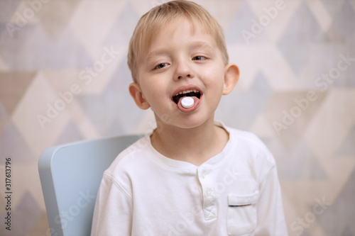 Child boy 5-6 years old with a tablet in his mouth. Home treatment.